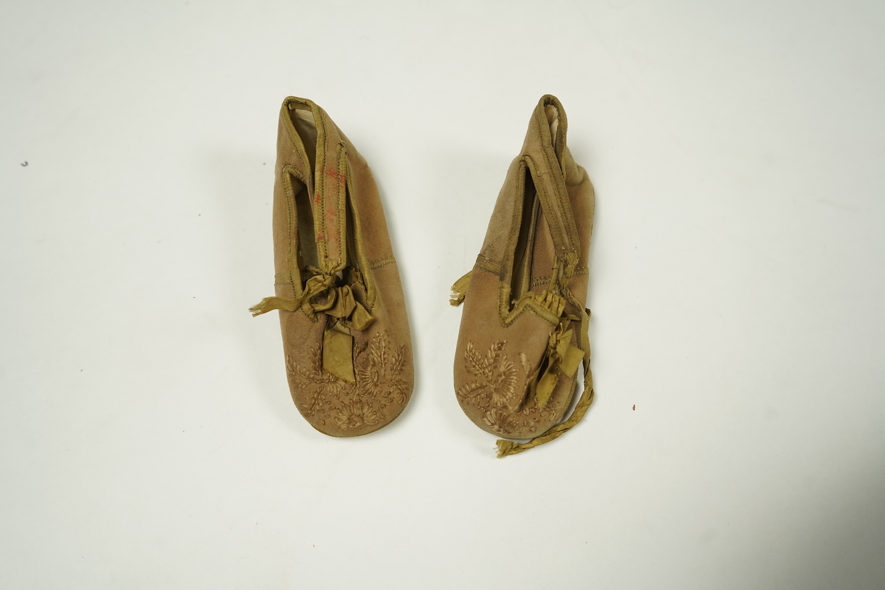 An unusual pair of Edwardian ladies red velvet and gold embroidered mules, a pair of 19th century ladies cream silk shoes and a pair of baby's embroidered suede shoes. Mules stamped 41at toe of sole. Condition - all thre